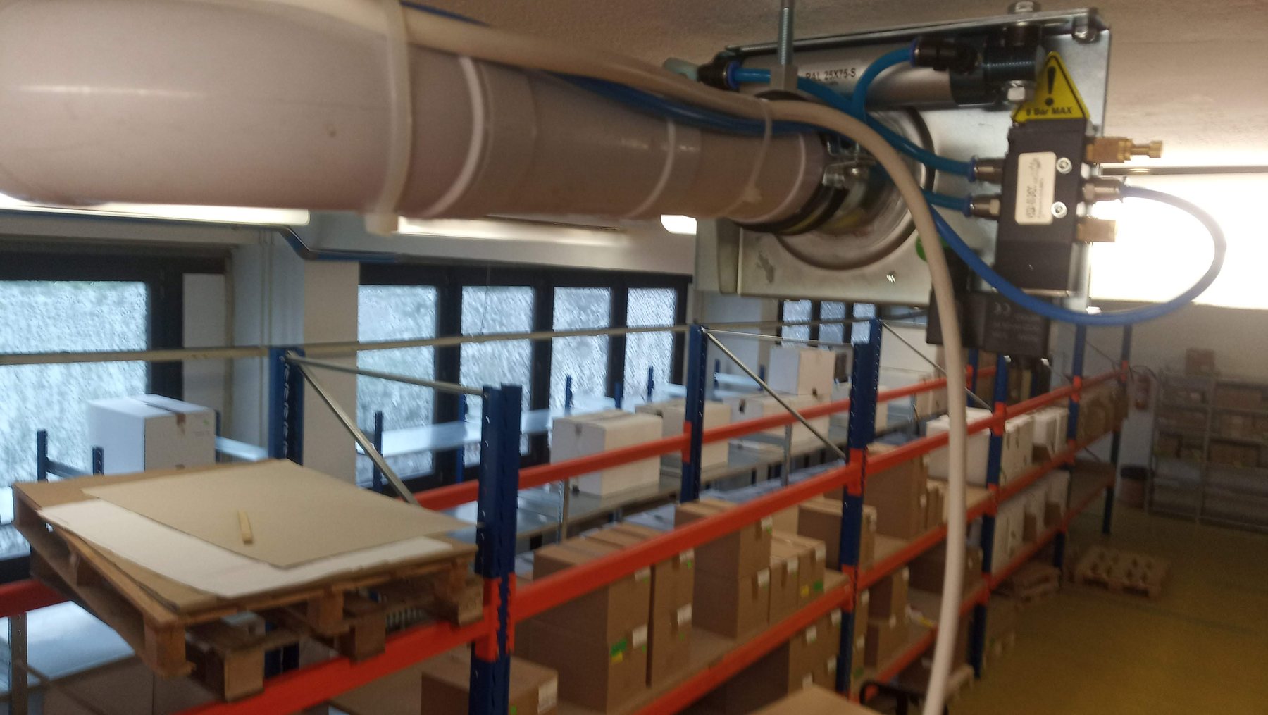 Potrubní rozvody centrálního odsávání vedené nad balicí linkou